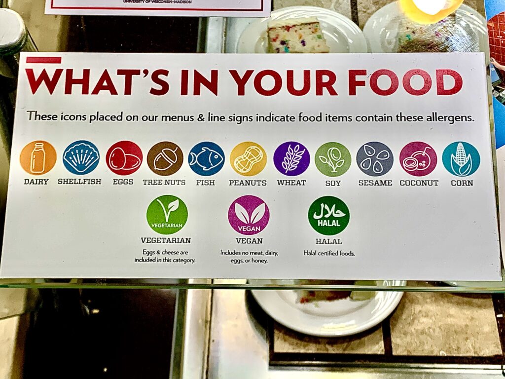A ‘WHAT’S IN YOUR FOOD’ warning label displayed on the dessert venue in Gordon Avenue Market. The label includes various icons and colors to represent the "top-nine" allergens and food preferences like vegetarian, vegan, and halal.